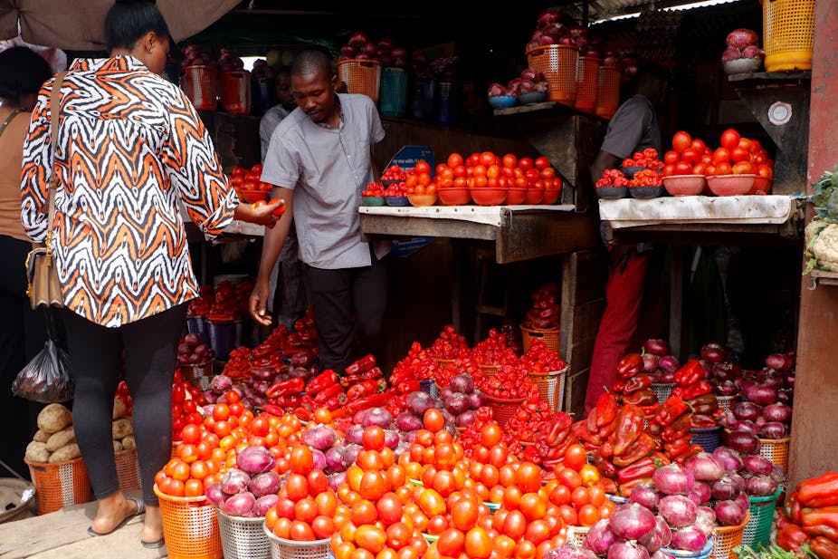 Women and men standing over farm produce in a marketplace