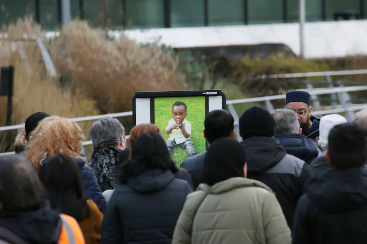 A crowd of people with a photograph of a little boy.