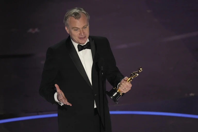 A man in a tuxedo holding a gold statue.