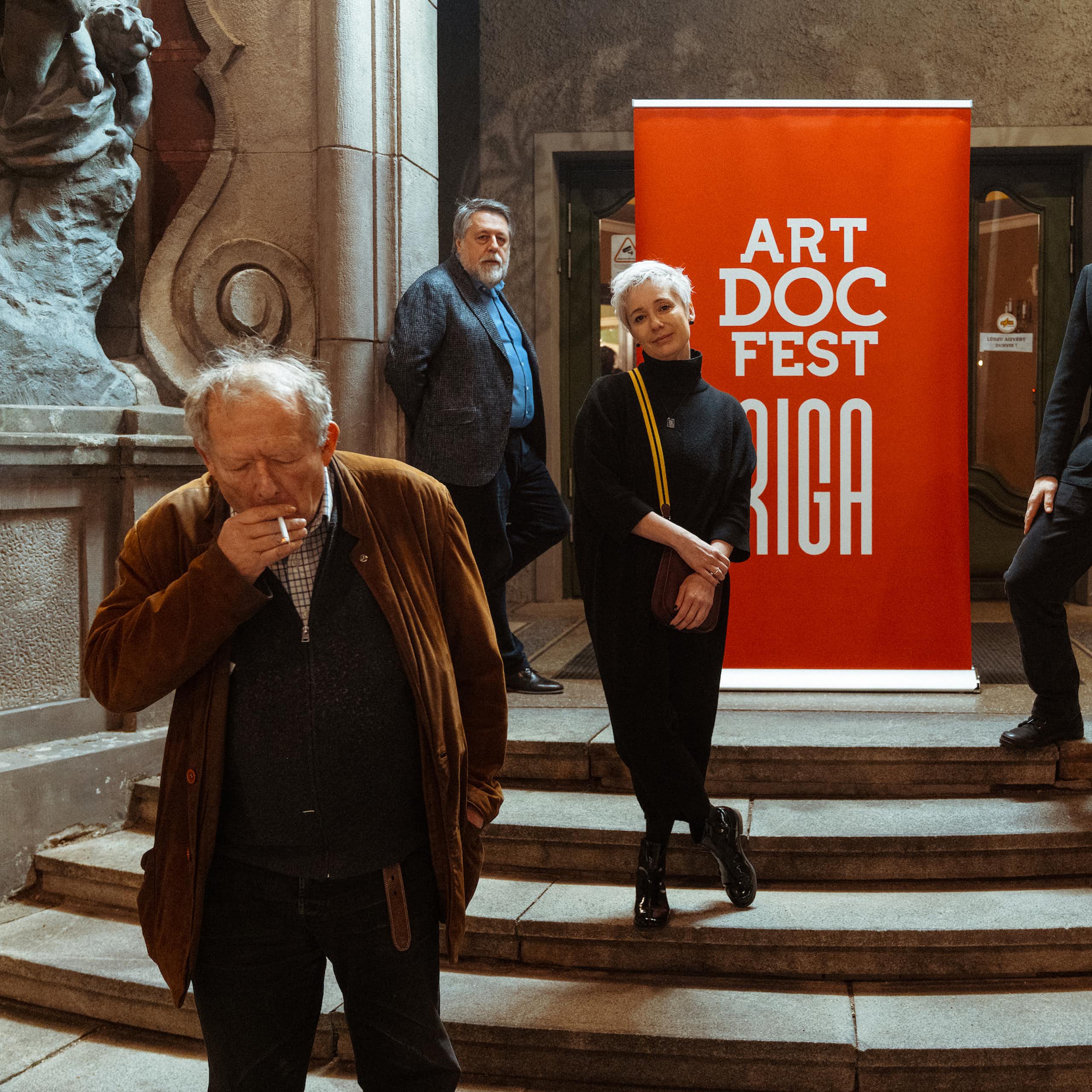 Four people stand in front of a sign for Art Doc Fest Riga