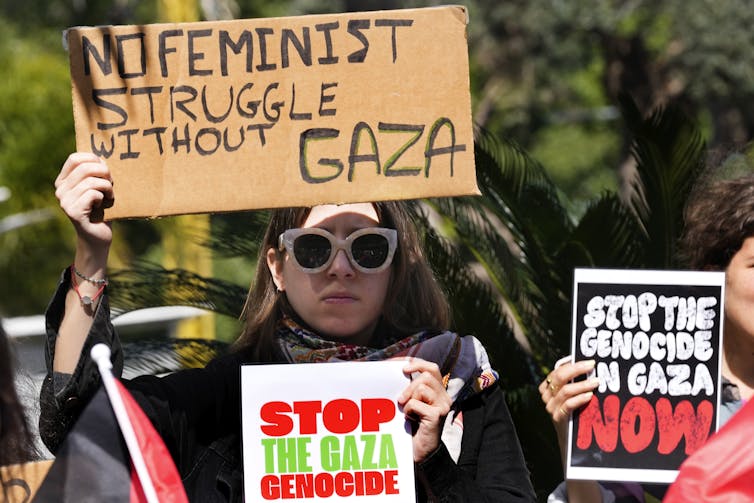A woman at a protest holds a placard reading: no feminist struggle without Gaza