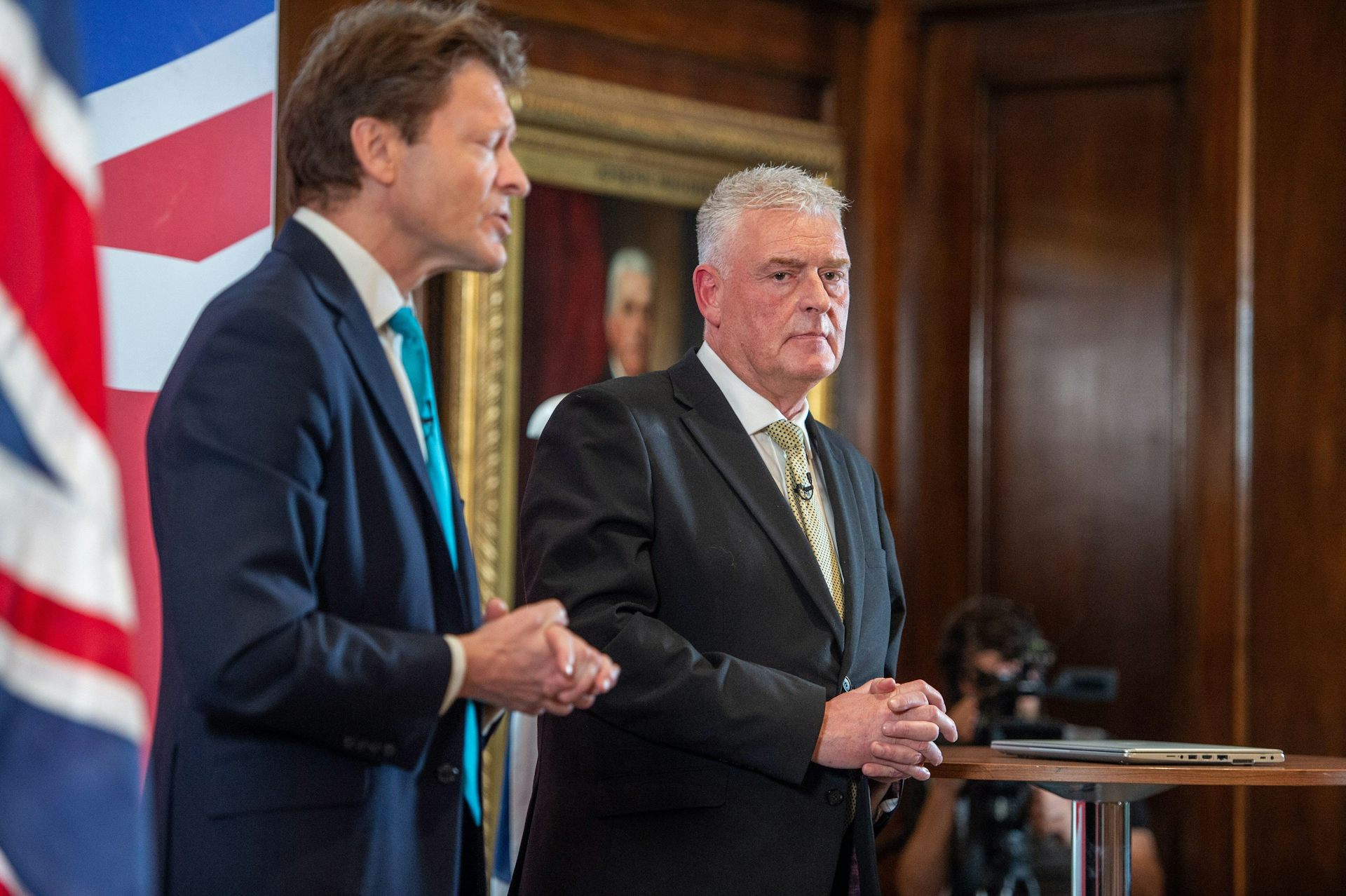 Richard Tice and Lee Anderson speaking at lecterns in front of a union flag.