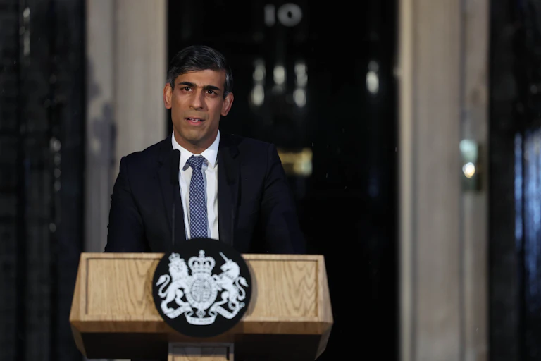 Rishi Sunak standing at a lectern in front of 10 Downing street in the dark