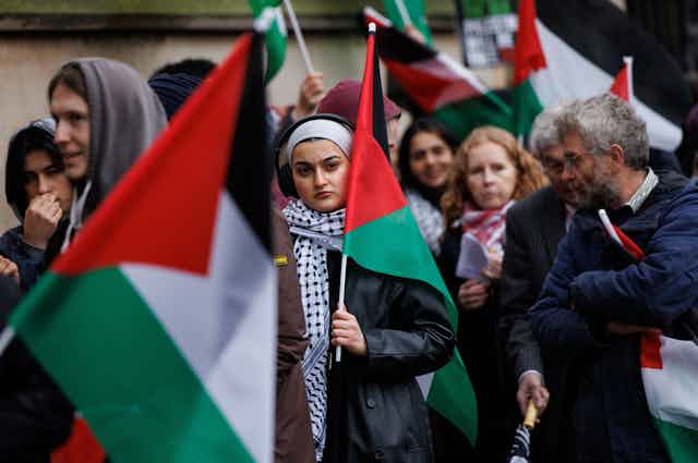 Protesters walking in London carrying large Palestinian flags.