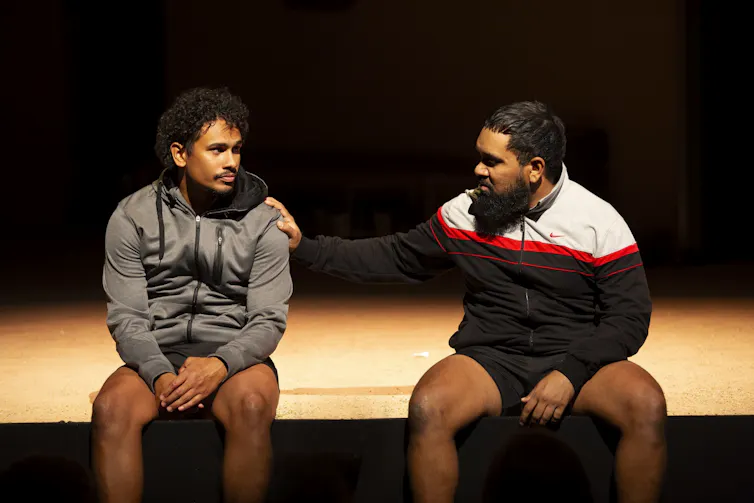 Ngali Shaw and Tibian Wyles sit on the edge of the stage.