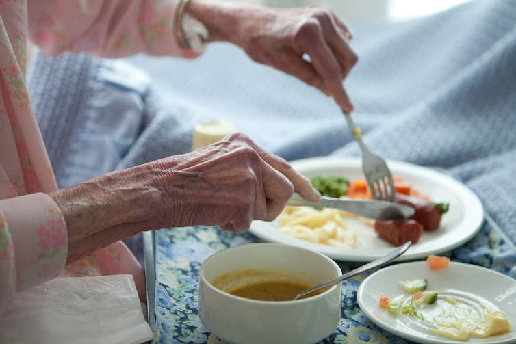 Aged care resident eats dinner from a tray