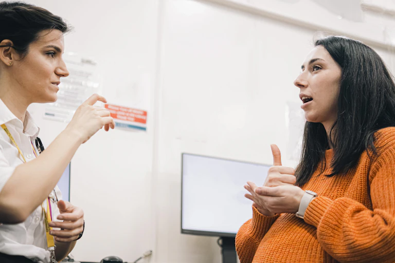 two women in health setting using sign to communicate