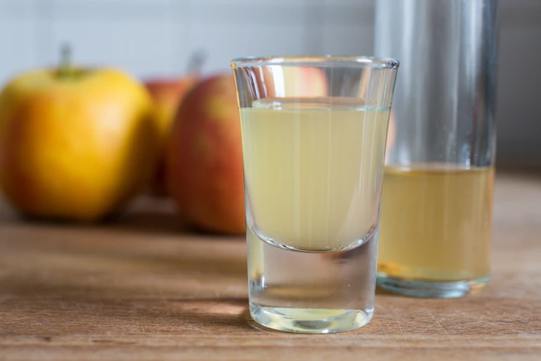 shot glasses of cloudy apple drink