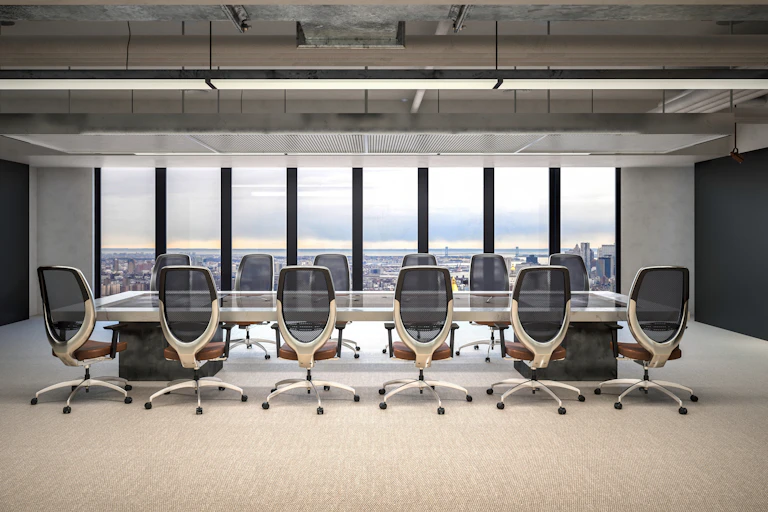A conference room with glass walls has a large table with a dozen chairs.