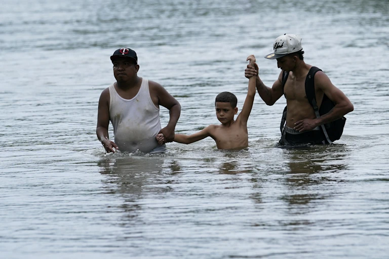 Two adults and one child are waist and chest deep in water.