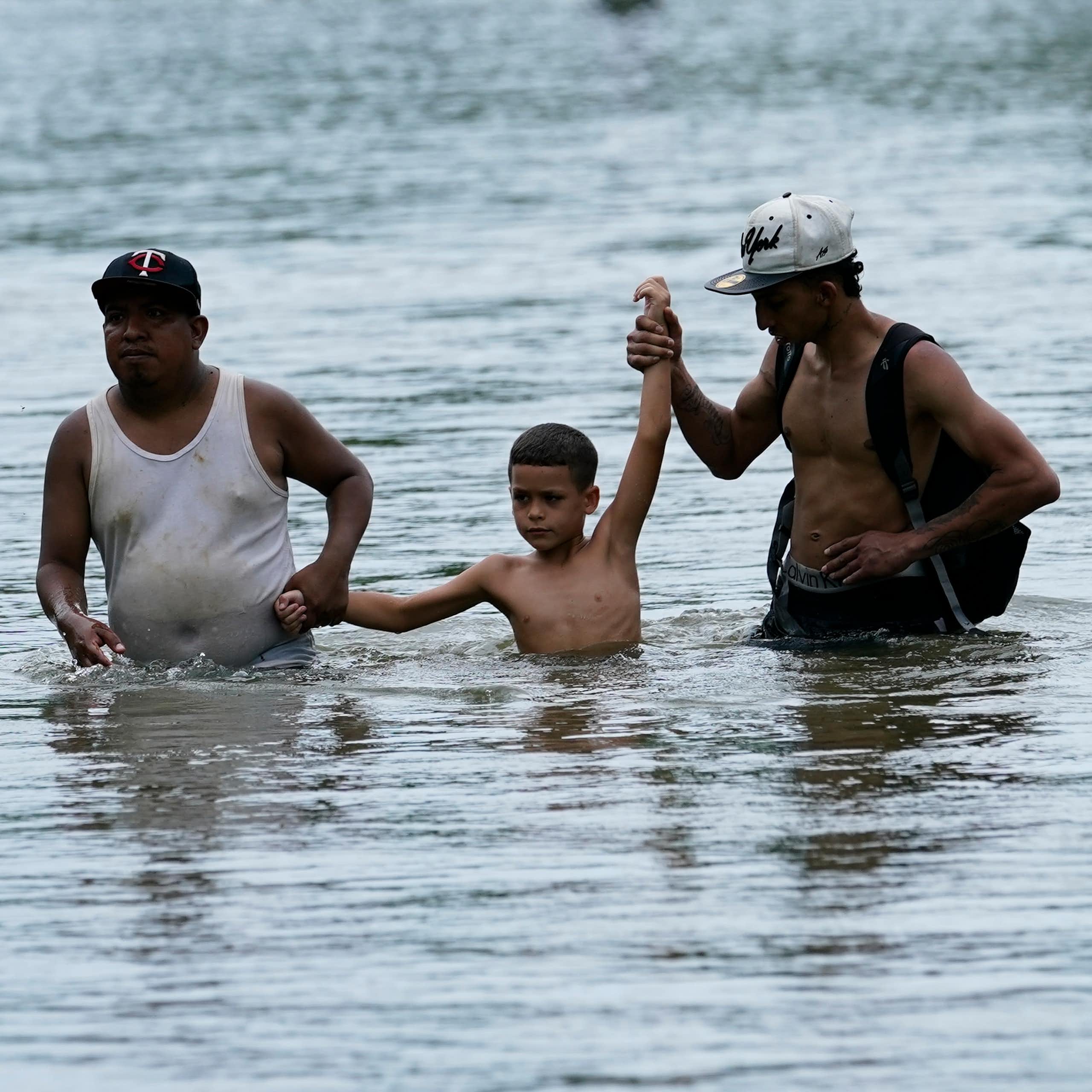 Two adults and one child are waist and chest deep in water.