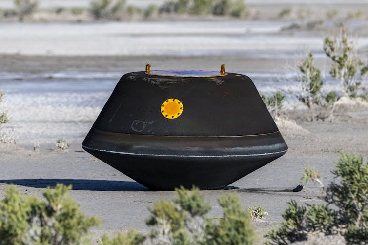 The sample return capsule, a black box, is on the ground after landing.