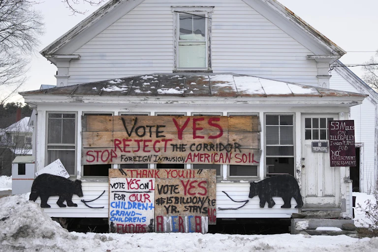 A rural home with large signs on it rejecting a utility corridor from Canada.