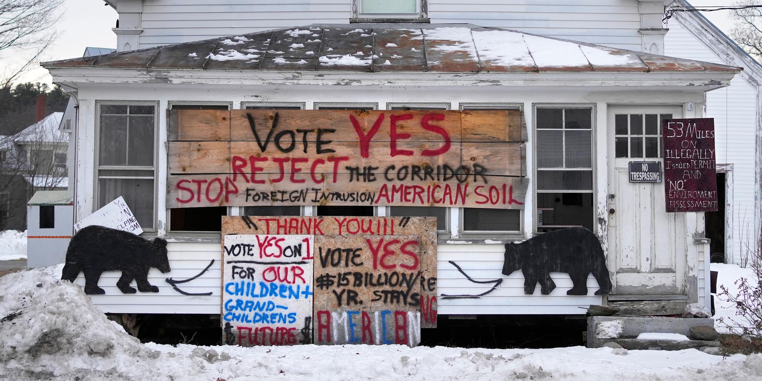 A rural home with large signs on it rejecting a utility corridor from Canada.