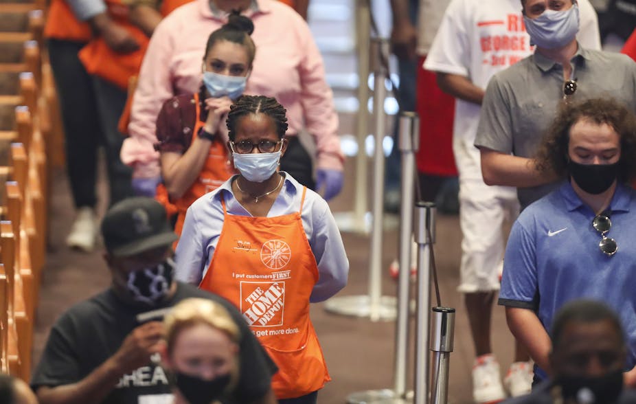 People in Home Depot aprons appear somber while standing in bleachers