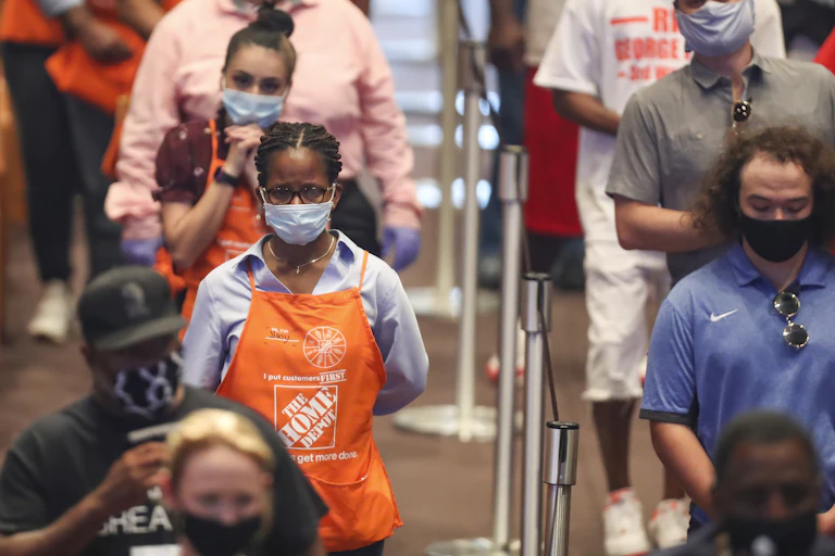 People in Home Depot aprons appear somber while standing in bleachers
