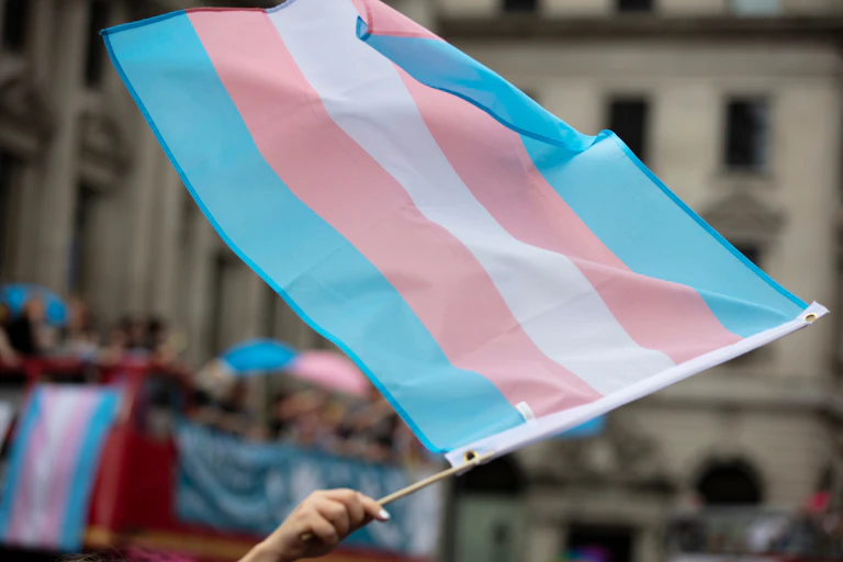 A transgender pride flag being waved