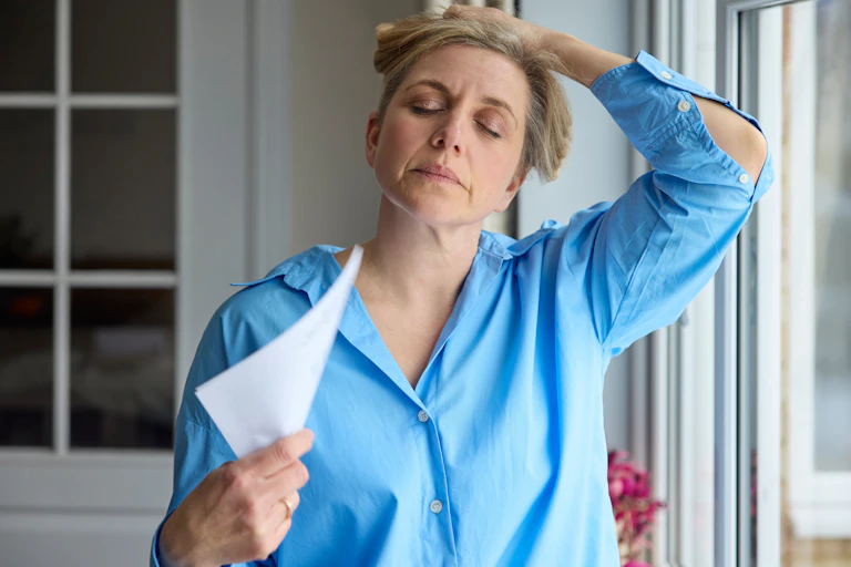 Menopausal woman lifts her hair and fans herself