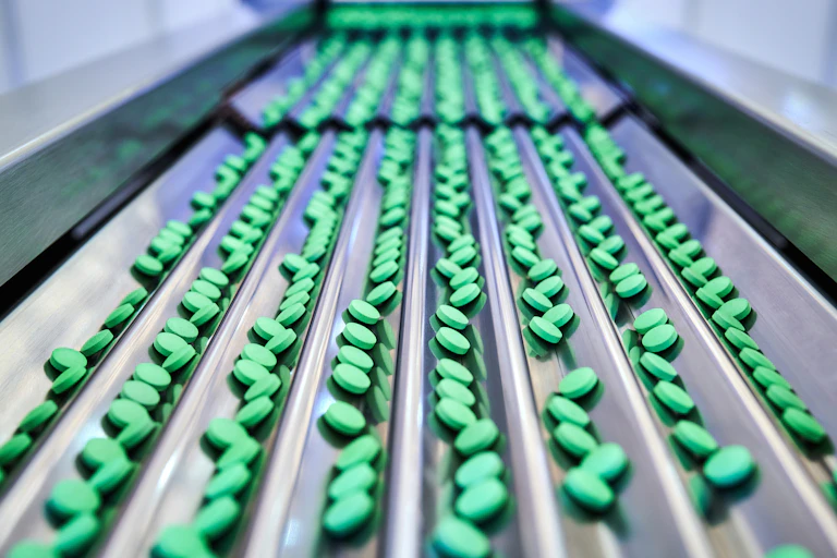 A conveyor belt of green pills