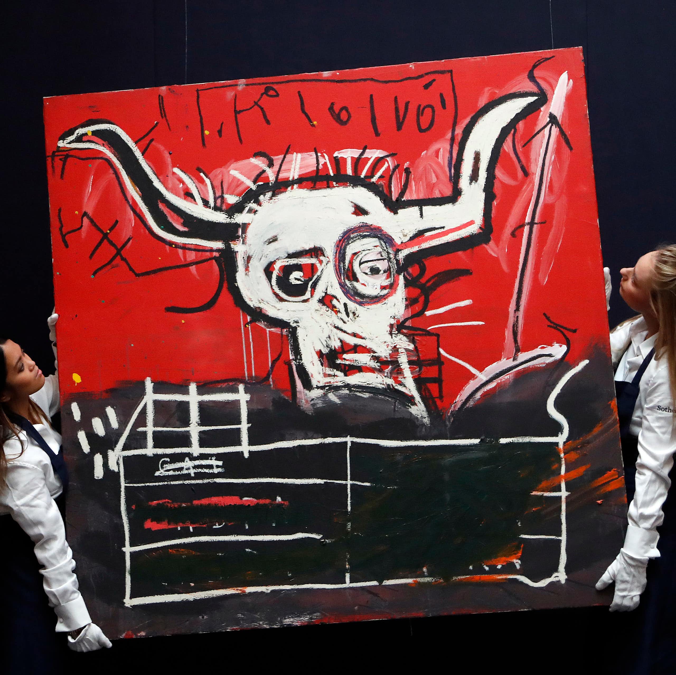 Two women carry a painting by Basquiat.