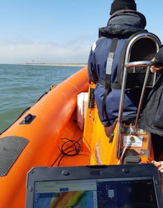 A scientist with a laptop on a boat.