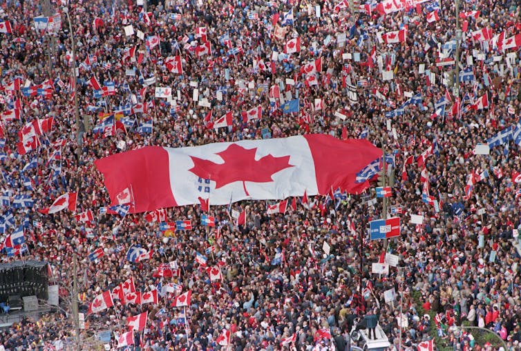 Se vio una gran bandera canadiense que siguió en medio de una gran multitud de personas.