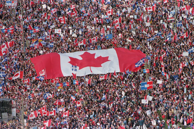 A large Canadian flag is seen being passed amid a huge crowd of people.