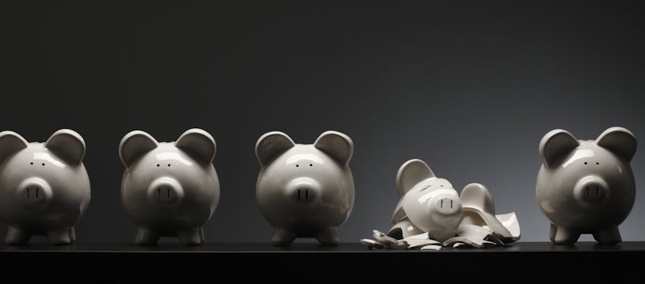 Four ceramic piggy banks and one that is shattered into pieces