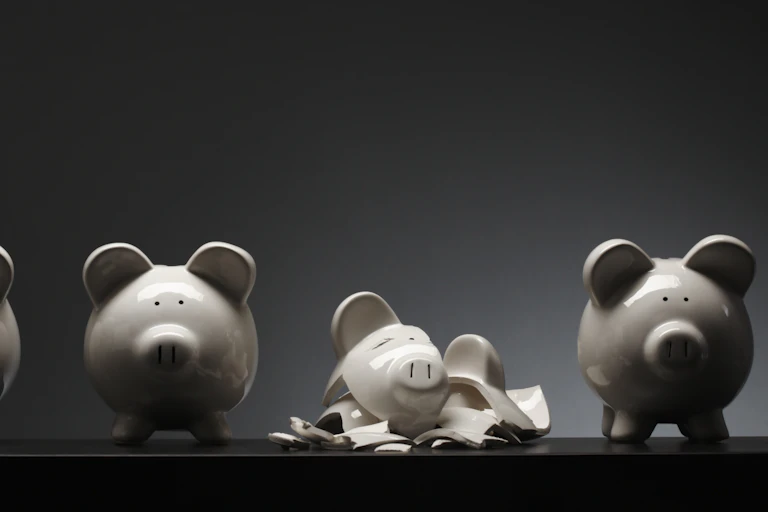 Four ceramic piggy banks and one that is shattered into pieces