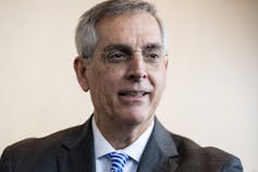 A close-up of a man in a suit and tie.