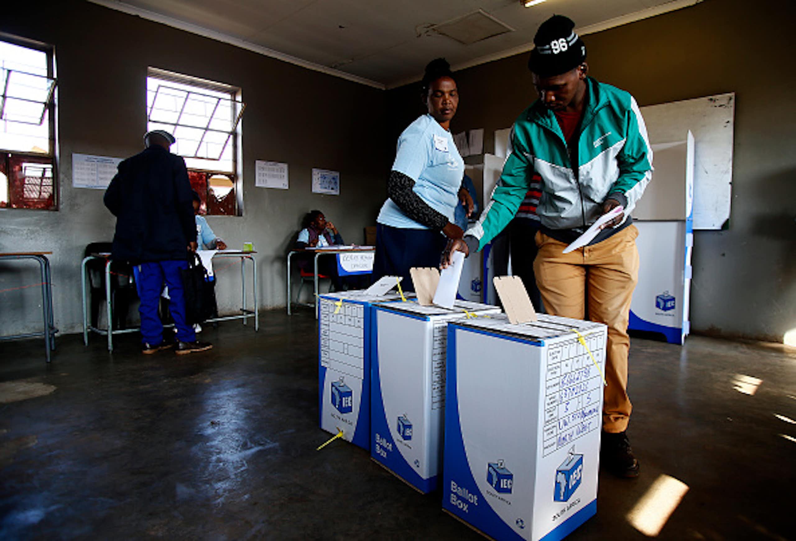 A man casts his ballot in a box marked 'IEC'.