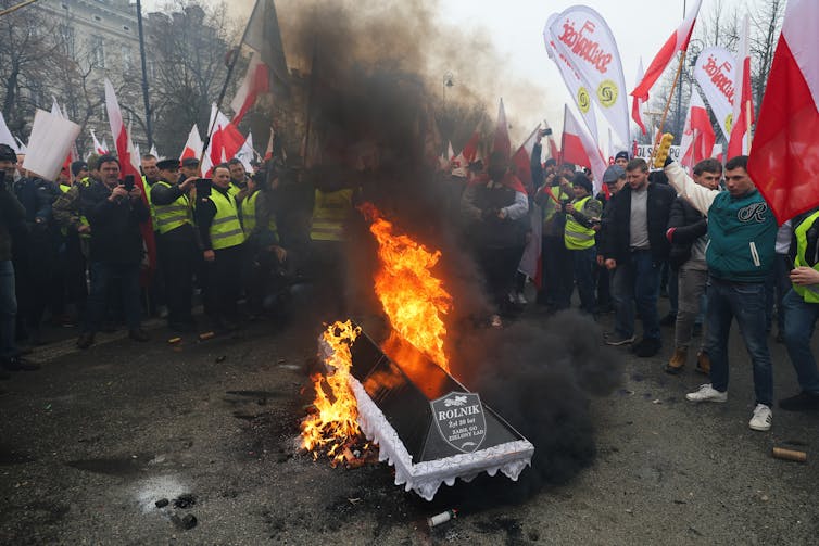 Protesters surround a coffin on fire.