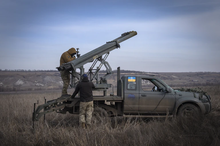 soldiers standing on the back of a pick-up truck with rocket launchers