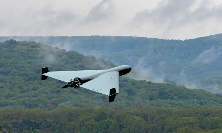 a plane-shaped drone flies over forested hills