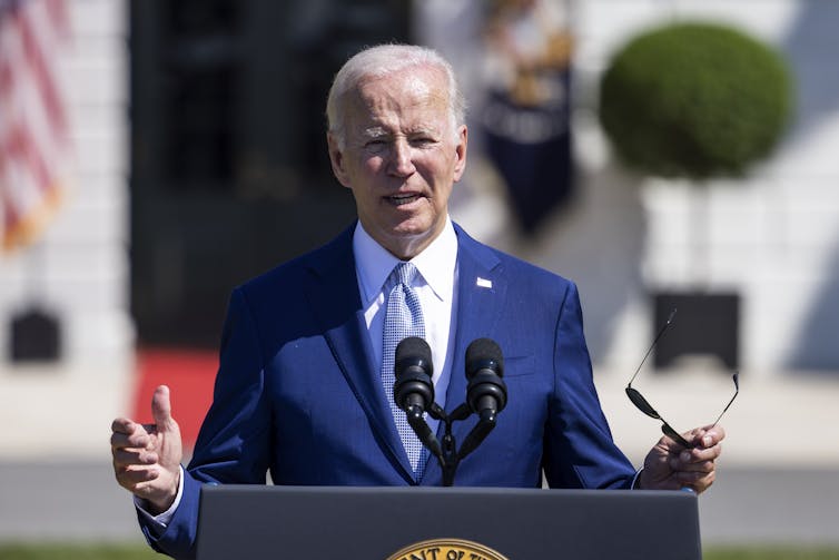 Joe Biden wearing a blue suit with his hands outstretched.