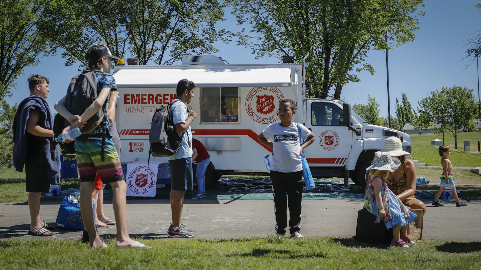 An emergency services vehicle sits in a parking lot behind a group of people
