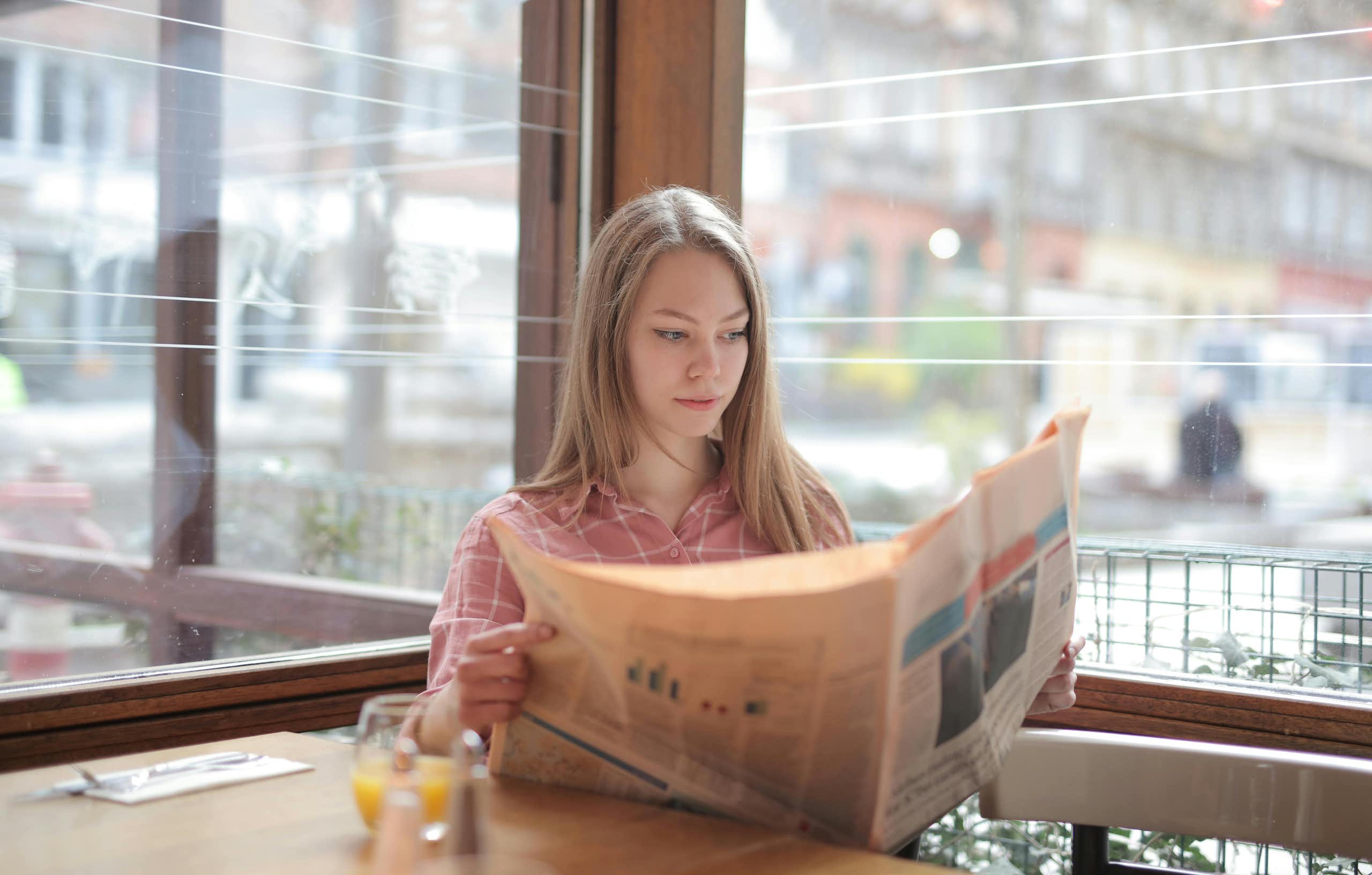 A woman reads the paper in a cafe.