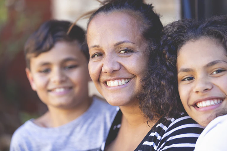 An Indigenous mother and her two children smile