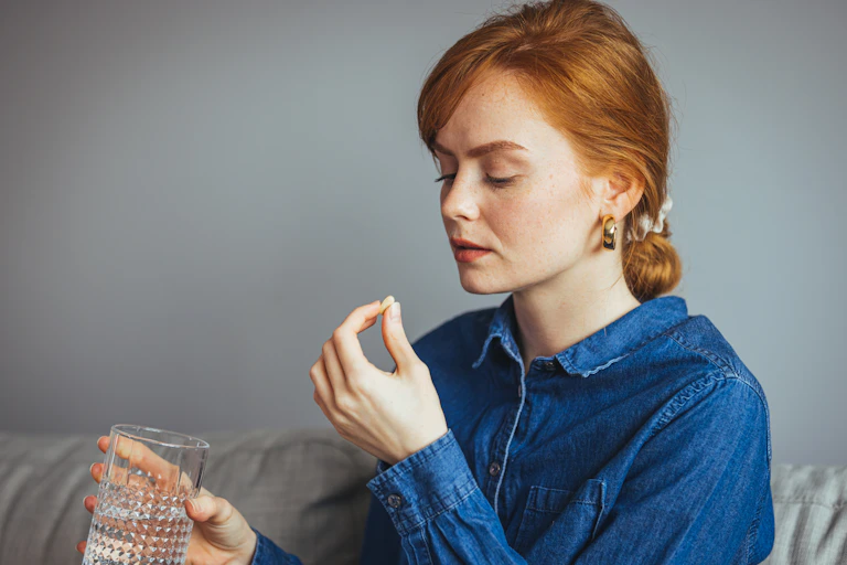 A young woman taking a pill.