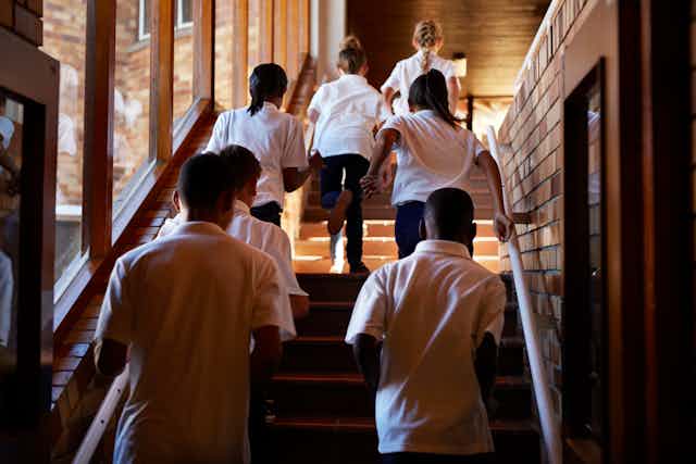 School students walk up a staircase. 