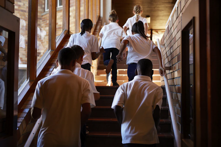 School students walk up a staircase.