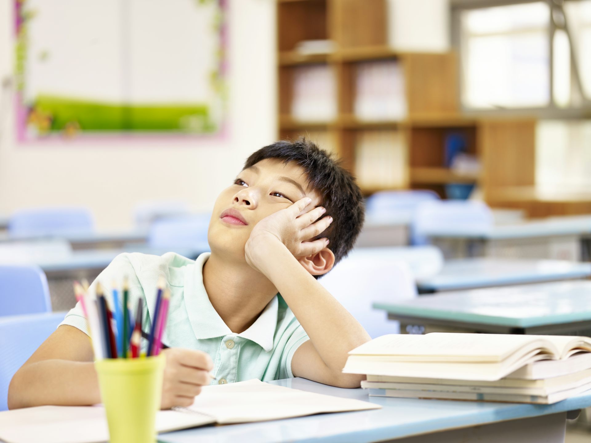 A boy thinking while doing schoolwork.