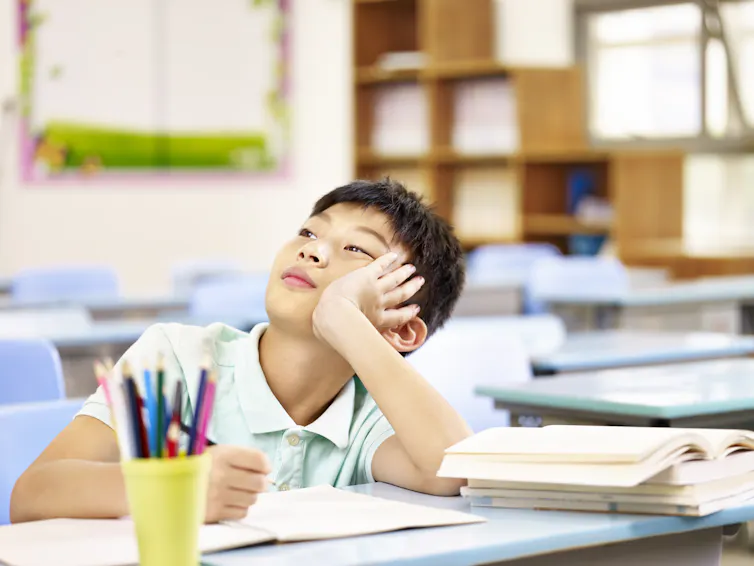 A boy thinking while doing schoolwork.