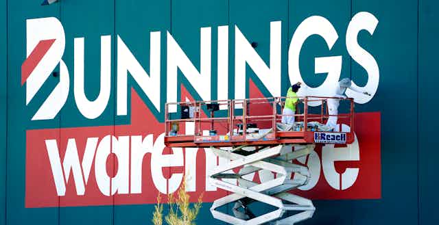 Workers repaint a Bunnings Warehouse sign