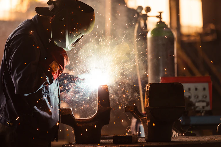 An industrial worker at a factory welding.