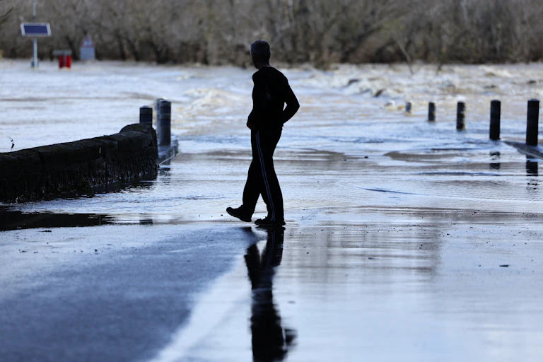 Un homme marche près d'un pont submergé suite à de fortes pluies dans le sud-est de la France à Dions dans le Gard, le 10 mars 2024.