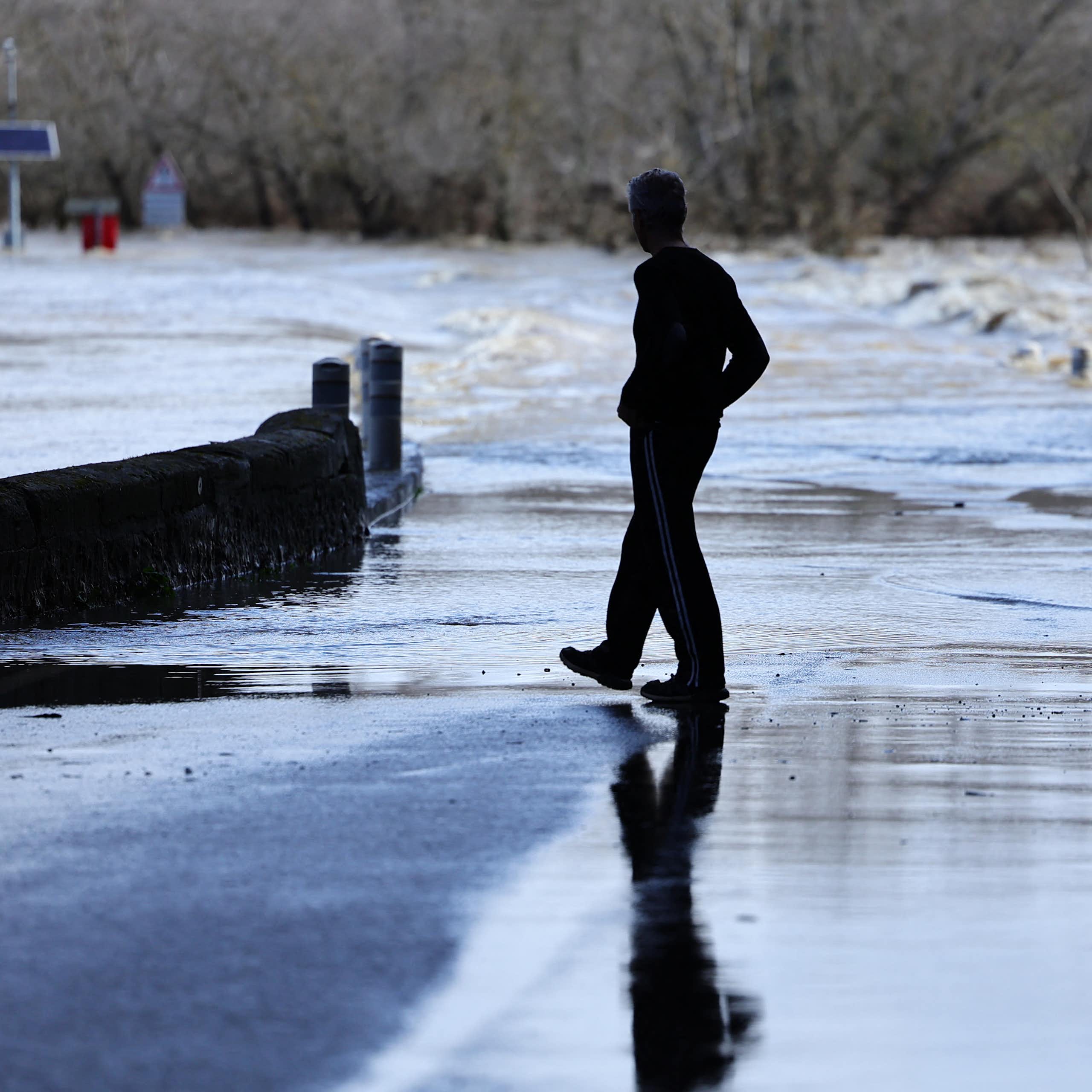 Un homme marche près d'un pont submergé suite à de fortes pluies dans le sud-est de la France à Dions dans le Gard, le 10 mars 2024. 