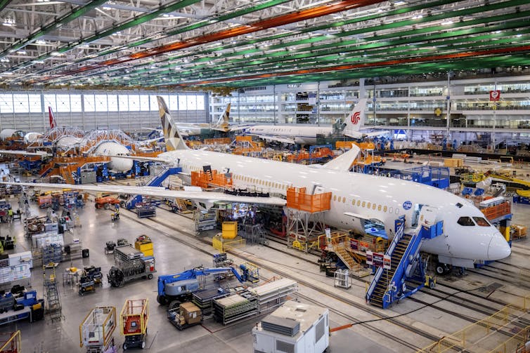 A plane being assembled by workers inside a factory
