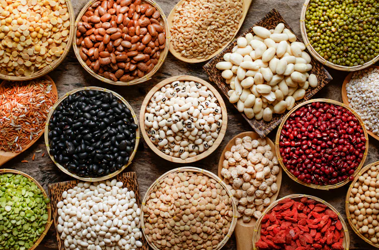 Flatlay shot looking down over a dozen or so colourful bowls of different beans, pulses, legumes