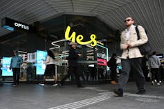 Shoppers walk in front of an Optus store